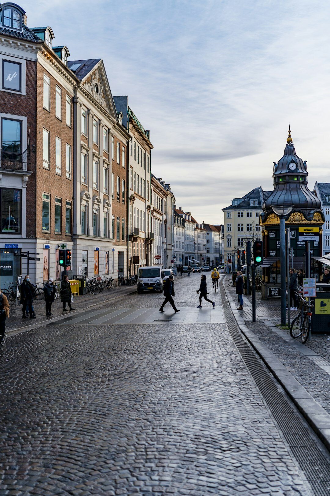 Cyclists riding past colorful old buildings on a Copenhagen street at dusk